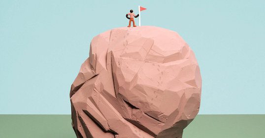 A man standing on top of a rock with a flag.