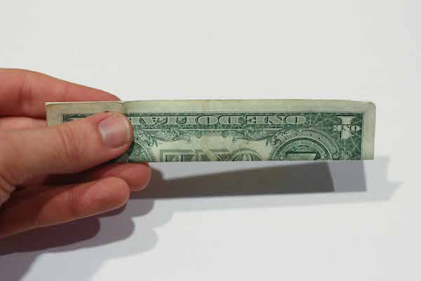 Folded one dollar bill in hand.