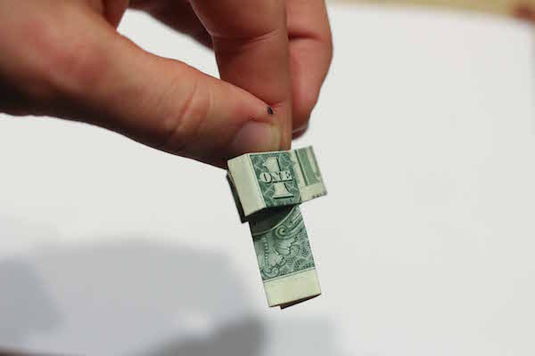 Folded and curled one dollar bill in hand.