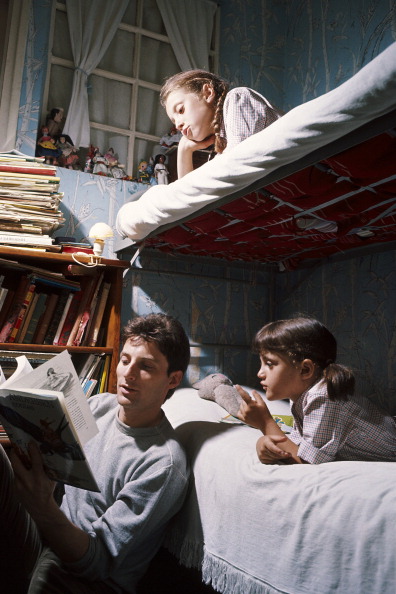 Vintage dad reading book for his daughters.