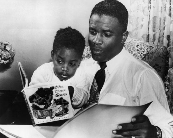 Vintage dad reading book with young son.