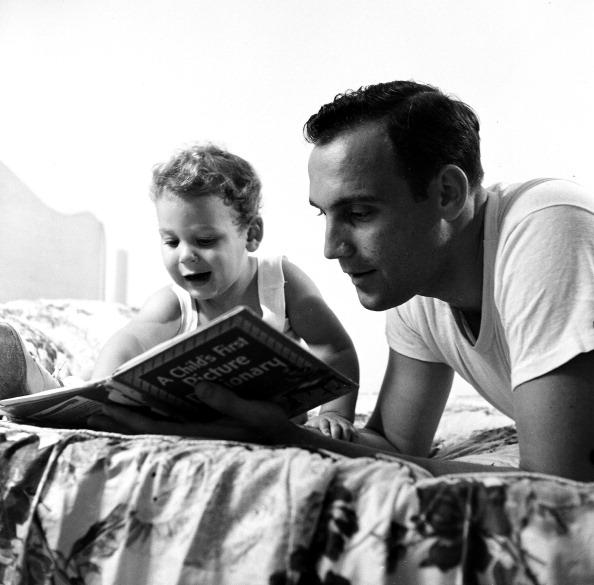 Vintage dad reading book with young son.