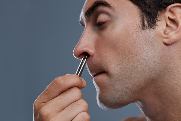 A man is using a brush to clean his nose.