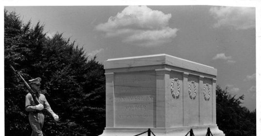 A soldier stands next to the inspiring tomb of the unknown soldier.