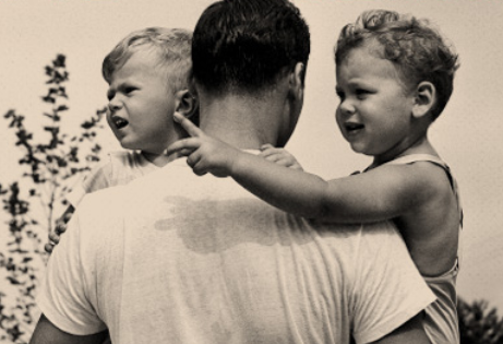 A black and white photo of a father and his two sons showcasing parenthood.