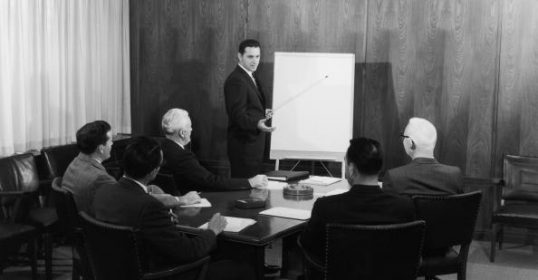 A man standing in front of a whiteboard during a meeting.