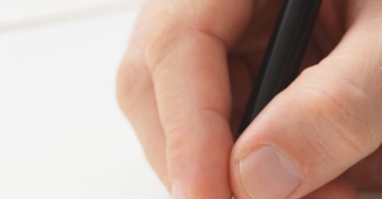 A person writing a thank you note with a pen after a job interview.