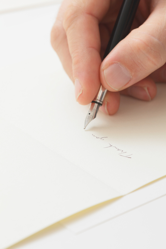 A person writing a thank you note with a pen after a job interview.