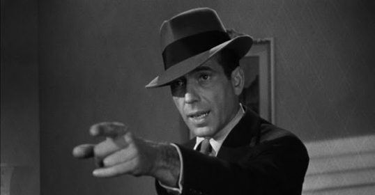 A man in a hat confidently pointing at something.