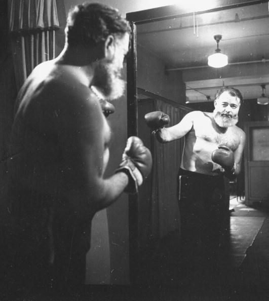 Hemingway in boxing gloves and watching him self in the mirror.