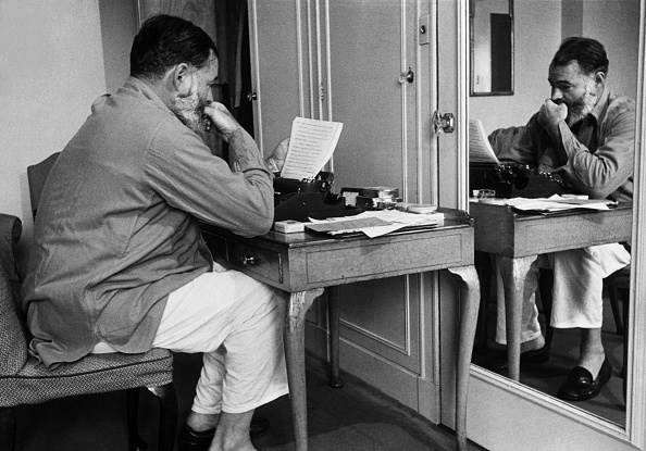 Hemingway reading notes while sitting in front of mirror.