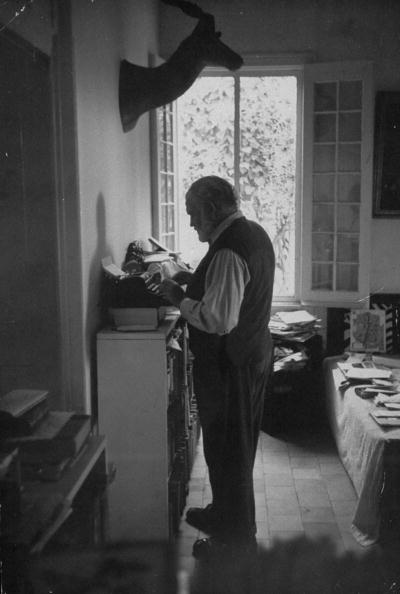 Hemingway writing by using typerwriter while standing.