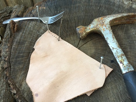 Making holes in a leather with nails and hammer.
