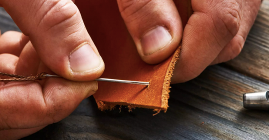 A person is using a tool to sew leather.