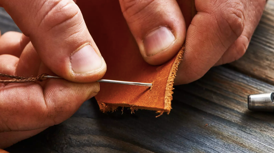 A person is using a tool to sew leather.