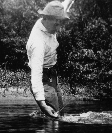 Vintage man in a river holding fishing string.
