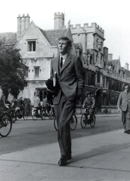 A vintage formal dressed man walking in the street with one hand in pocket.