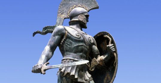 A statue of a Spartan warrior holding a shield, embodying the Spartan Way.