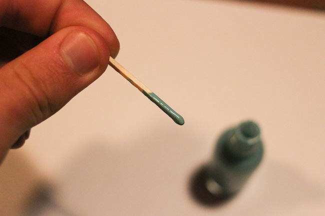 Closeup view of matchstick dipped in nail polish.