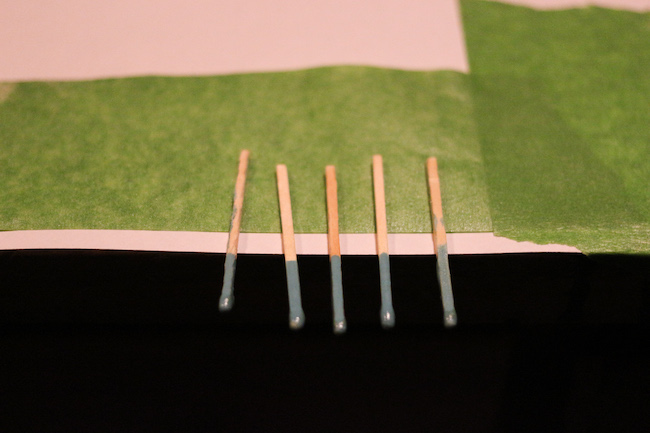 Five matchsticks dipped in nailpolish being displayed.