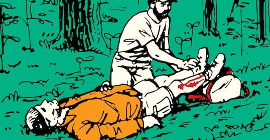 A person in a white shirt demonstrates the Skill of the Week by tending to another's leg injury in a forest. The injured individual, clad in an orange jacket, lies on the ground as they receive care and treatment for shock amidst the tranquil woodland setting.