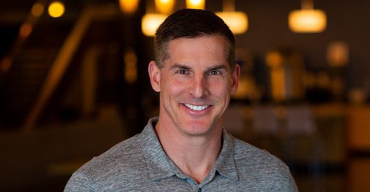 A smiling man in a gray shirt.
