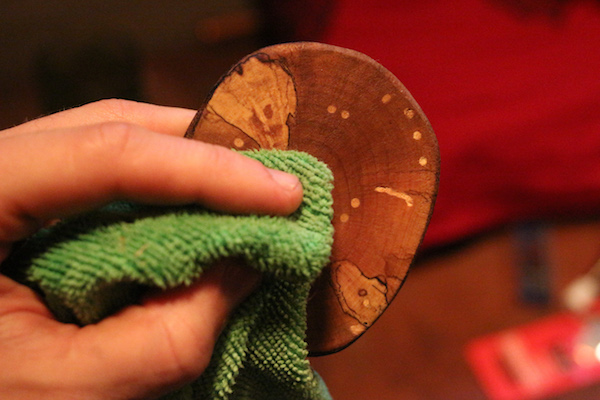 Wiping wooden coaster with microfiber cloth.