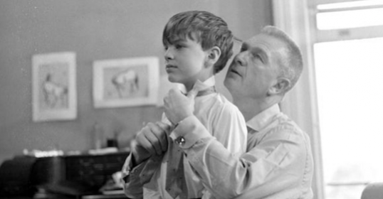 A father helping his son with tie style.