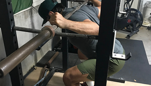 A man doing squats in a gym to treat his tendonitis.