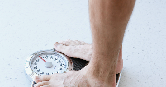 A man is standing on a scale trying to lose weight.