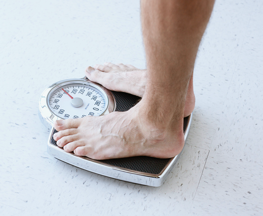 A man is standing on a scale trying to lose weight.