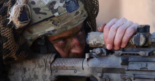 A soldier in camouflage is holding a rifle, showcasing the history of America's Special Forces.
