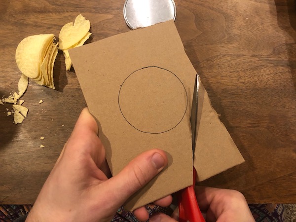 Cutting of Pringles marked bottom with scissor.