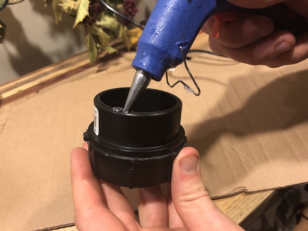 Gluing one of your PVC fittings to the cardboard circle.