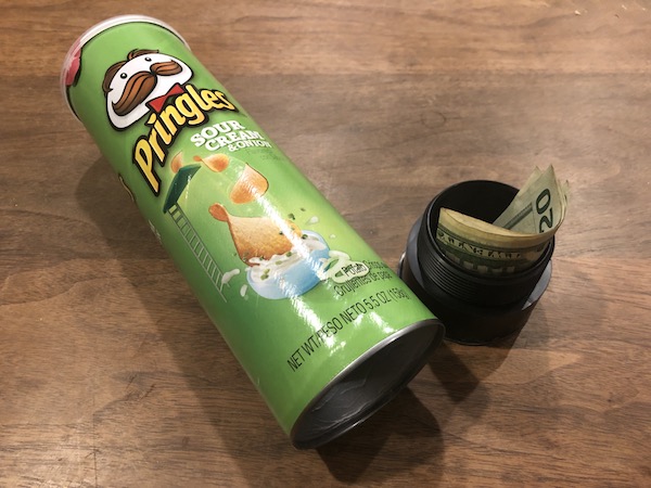 A can of potato chips sits beside a can of money.
