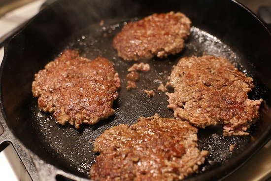 Crusted burger in a fry pan.