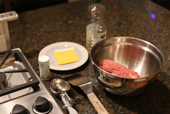 Mashed meat in a bowl and utensils around in a kitchen. 