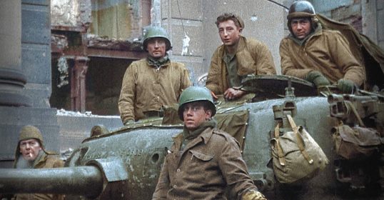 During WWII, a group of Tank Gunners standing on top of a tank.