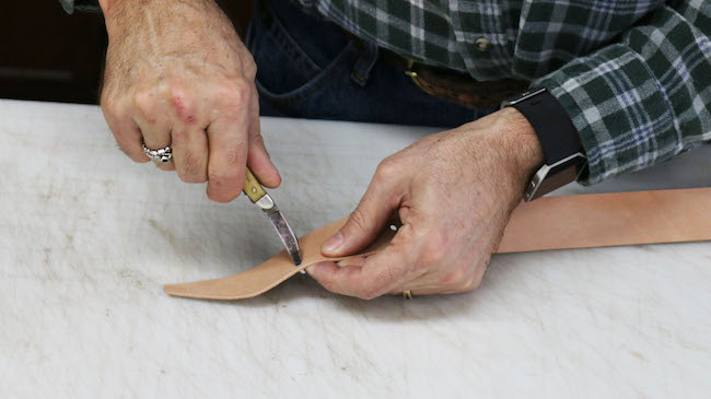 Cutting the leather strip by a knife.