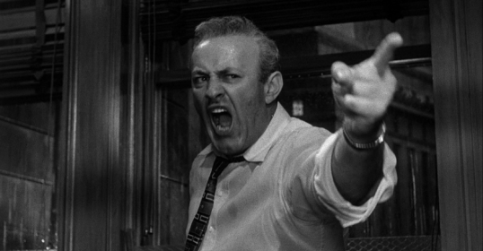 The man is pointing angrily at the door.