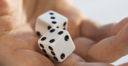 Two white dice in a person's hand, potentially bringing some luck.