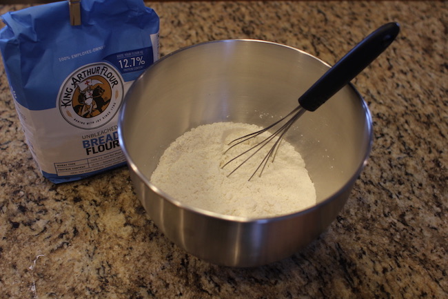 Whisking flour, salt, and yeast together in a bowl.