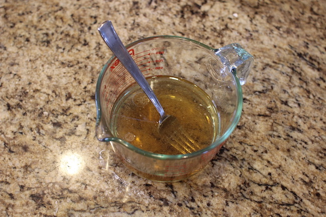 Water, oil and brown sugar mixed in a cup.