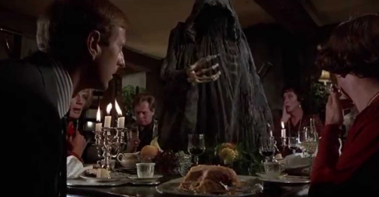 A group of people sitting around a table with a ghost during Death Over Dinner.