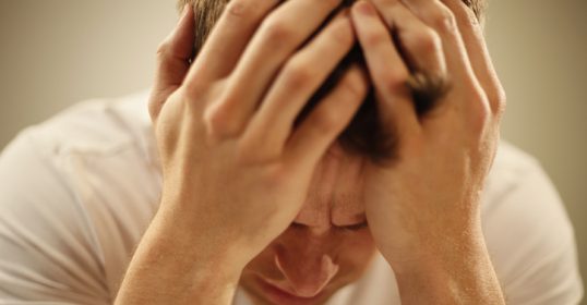 A man clutching his head.