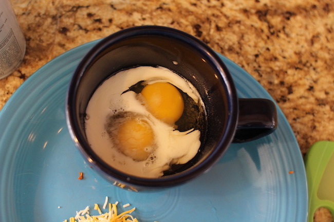 Two cracked eggs in a mug.
