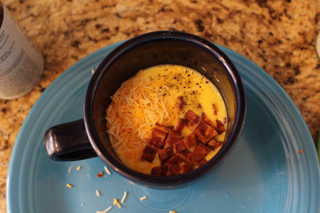 Cheese scrambled eggs and sausage stirred in cup.