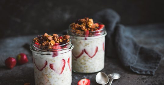 Two jars of overnight oats with strawberries and granola, perfect for breakfast on the go.