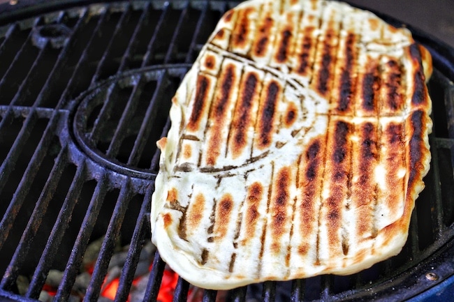 Cooked side of pizza dough on grill.