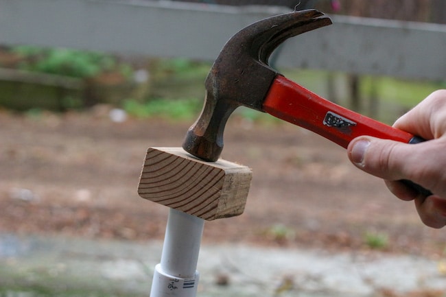 Hammer pounding the PVC pipe with the help of wooden box.